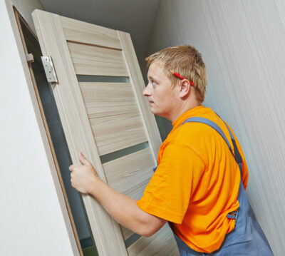 Male handyman carpenter at interior wood door installation
